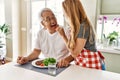 Middle age hispanic couple smiling happy eating beef with salad at the kitchen Royalty Free Stock Photo