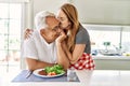 Middle age hispanic couple smiling happy eating beef with salad at the kitchen Royalty Free Stock Photo