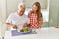 Middle age hispanic couple smiling happy eating beef with salad at the kitchen Royalty Free Stock Photo