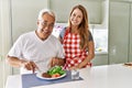 Middle age hispanic couple smiling happy eating beef with salad at the kitchen Royalty Free Stock Photo