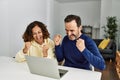 Middle age hispanic couple smiling happy with fists raised up