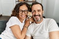 Middle age hispanic couple smiling happy sitting on the sofa holding dog at home Royalty Free Stock Photo