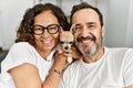 Middle age hispanic couple smiling happy sitting on the sofa holding dog at home Royalty Free Stock Photo