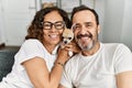 Middle age hispanic couple smiling happy sitting on the sofa holding dog at home Royalty Free Stock Photo