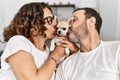 Middle age hispanic couple smiling happy sitting on the sofa kissing dog at home Royalty Free Stock Photo