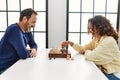 Middle age hispanic couple smiling happy sitting on the table playing chess at home Royalty Free Stock Photo