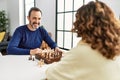 Middle age hispanic couple smiling happy sitting on the table playing chess at home Royalty Free Stock Photo