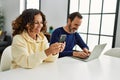 Middle age hispanic couple smiling happy using laptop and smartphone at home Royalty Free Stock Photo