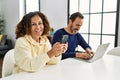 Middle age hispanic couple smiling happy using laptop and smartphone at home Royalty Free Stock Photo