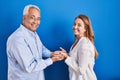 Middle age hispanic couple standing over blue background pointing aside with hands open palms showing copy space, presenting Royalty Free Stock Photo