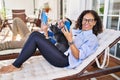 Middle age hispanic couple using smartphone and touchpad lying on hammock with dog at terrace Royalty Free Stock Photo