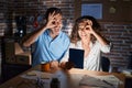 Middle age hispanic couple using touchpad sitting on the table at night doing ok gesture with hand smiling, eye looking through Royalty Free Stock Photo