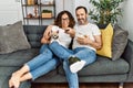 Middle age hispanic couple watching movie and eating popcorn sitting on the sofa at home Royalty Free Stock Photo
