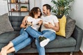 Middle age hispanic couple watching movie and eating popcorn sitting on the sofa at home Royalty Free Stock Photo