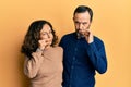 Middle age hispanic couple wearing casual clothes mouth and lips shut as zip with fingers Royalty Free Stock Photo