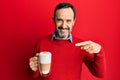 Middle age hispanic man drinking a cup of cappuccino coffee pointing finger to one self smiling happy and proud Royalty Free Stock Photo