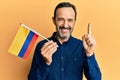 Middle age hispanic man holding colombia flag smiling with an idea or question pointing finger with happy face, number one Royalty Free Stock Photo