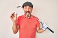 Middle age hispanic man holding golf club and ball celebrating crazy and amazed for success with open eyes screaming excited Royalty Free Stock Photo