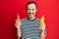 Middle age hispanic man holding ketchup and mustard bottle smiling with a happy and cool smile on face