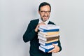Middle age hispanic man holding a pile of books smiling looking to the side and staring away thinking Royalty Free Stock Photo