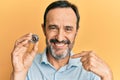 Middle age hispanic man holding virtual currency bitcoin pointing finger to one self smiling happy and proud