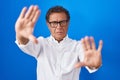 Middle age hispanic man standing over blue background doing frame using hands palms and fingers, camera perspective Royalty Free Stock Photo