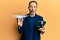 Middle age hispanic man using drone making fish face with mouth and squinting eyes, crazy and comical