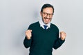 Middle age hispanic man wearing casual clothes and glasses excited for success with arms raised and eyes closed celebrating Royalty Free Stock Photo