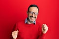 Middle age hispanic man wearing casual clothes and glasses excited for success with arms raised and eyes closed celebrating Royalty Free Stock Photo