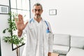 Middle age hispanic man wearing doctor uniform and stethoscope at waiting room doing stop sing with palm of the hand Royalty Free Stock Photo