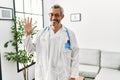 Middle age hispanic man wearing doctor uniform and stethoscope at waiting room showing and pointing up with fingers number five Royalty Free Stock Photo