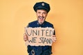 Middle age hispanic man wearing police uniform holding united we stand banner smiling and laughing hard out loud because funny