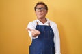 Middle age hispanic man wearing professional cook apron looking at the camera blowing a kiss with hand on air being lovely and