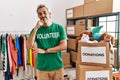 Middle age hispanic man wearing volunteer t shirt at donations stand looking confident at the camera smiling with crossed arms and Royalty Free Stock Photo