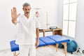 Middle age hispanic therapist man working at pain recovery clinic doing stop sing with palm of the hand Royalty Free Stock Photo