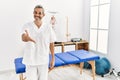 Middle age hispanic therapist man working at pain recovery clinic smiling friendly offering handshake as greeting and welcoming Royalty Free Stock Photo