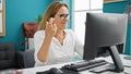 Middle age hispanic woman business worker looking computer crossing fingers at the office