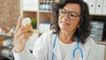 Middle age hispanic woman doctor holding bottle of pills at the clinic Royalty Free Stock Photo