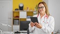 Middle age hispanic woman doctor smiling using touchpad at the clinic Royalty Free Stock Photo