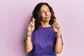 Middle age hispanic woman doing fingers crossed gesture smiling looking to the side and staring away thinking Royalty Free Stock Photo