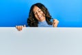 Middle age hispanic woman holding blank empty banner very happy and excited doing winner gesture with arms raised, smiling and