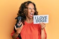 Middle age hispanic woman holding chihuahua dog and paper with i love dogs phrase angry and mad screaming frustrated and furious,