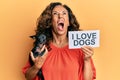 Middle age hispanic woman holding chihuahua dog and paper with i love dogs phrase angry and mad screaming frustrated and furious,