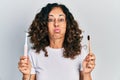 Middle age hispanic woman holding electric toothbrush and teethbrush puffing cheeks with funny face Royalty Free Stock Photo