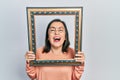 Middle age hispanic woman holding empty frame smiling and laughing hard out loud because funny crazy joke Royalty Free Stock Photo