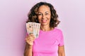 Middle age hispanic woman holding united kingdom pounds looking positive and happy standing and smiling with a confident smile