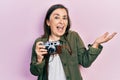 Middle age hispanic woman holding vintage camera celebrating achievement with happy smile and winner expression with raised hand Royalty Free Stock Photo