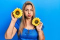 Middle age hispanic woman holding yellow sunflowers puffing cheeks with funny face Royalty Free Stock Photo