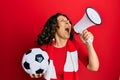 Middle age hispanic woman hooligan screaming through megaphone supporting soccer team