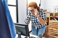 Middle age hispanic woman looking computer working at clothing store Royalty Free Stock Photo